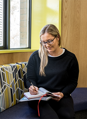 A Deakin arts student writing in a notebook