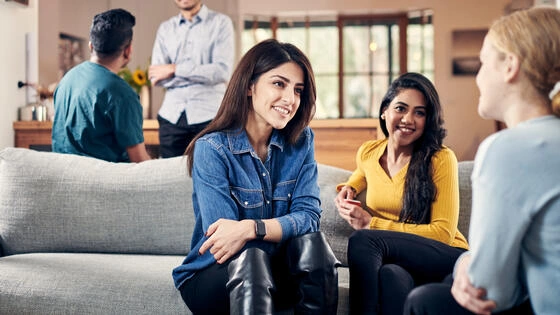 Three Deakin English student sit on a couch talking. 