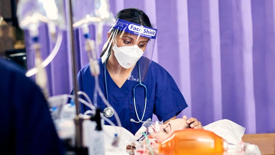 A Deakin postgraduate intensive care nursing student in PPE attends to a patient.