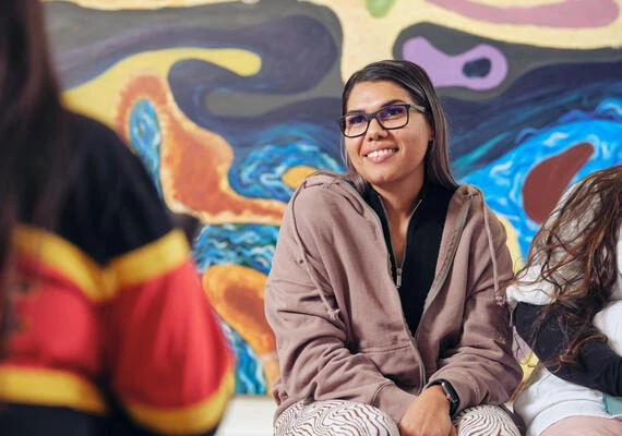 Deakin student sitting on campus in front of artwork.