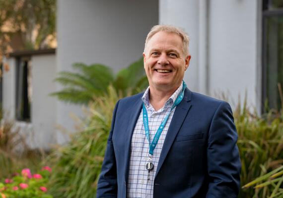 The Head of School of Education Damian Blake standing outside in front of a building, smiling. 