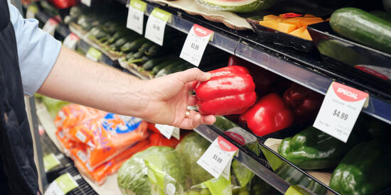Person picks up a capsicum at a grocery store.