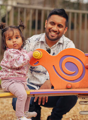 A parent watches their child playing outdoors on a playground.