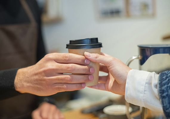A takeaway coffee cup being passed between two people
