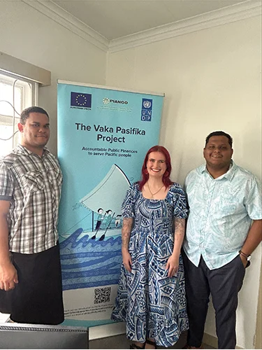 Sarah Fiji 2 Sarah stands with two people in front of a banner about the Vaka Pasifika program