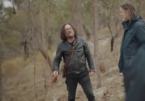 A screenshot from a video of Tyson Yunkaporta in the bush talking to someone.