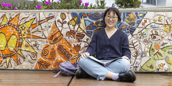 International student sitting against a colourful tiles mosaic wall