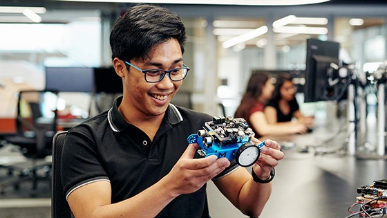 A Deakin IT students inspects a robot.