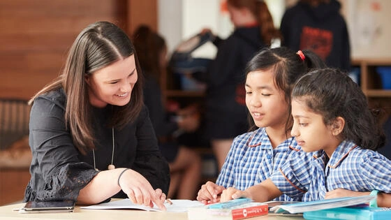 A Deakin postgraduate education teacher helps two students. 