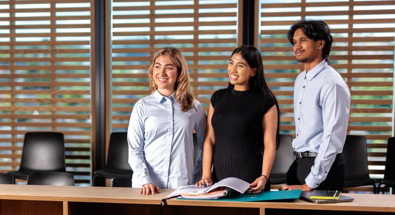 Three Law students standing in the Deakin Moot Court.