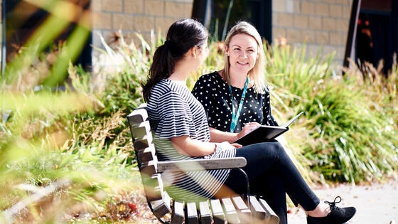 A Deakin postgraduate mental health nursing student sits on a bench with another person.