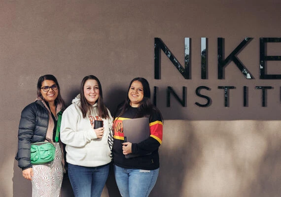Three students standing in front of the Deakin NIKERI Institute.