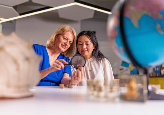 Lihua Xu Associate Professor in Science Education and PhD student Samantha Bothe in a classroom using a handheld magnifying glass.
