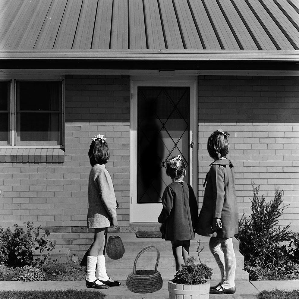 2022_Hayley_Millar_Baker.jpg A black and white photo of three children standing in front of a house