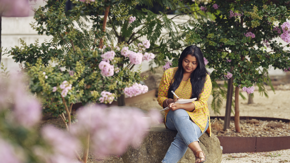 Student sits in a rose garden at the Deakin Burwood Campus in Melbourne.