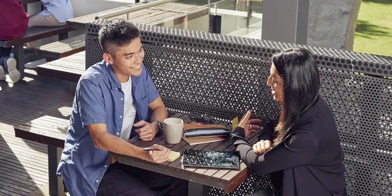 Two students sitting outdoors at a table