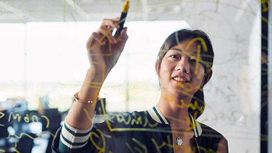 A Deakin IT student draws on a glass window.