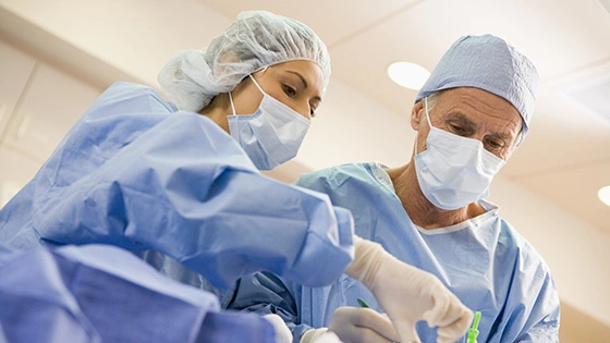 Two surgeons operating while wearing PPE.