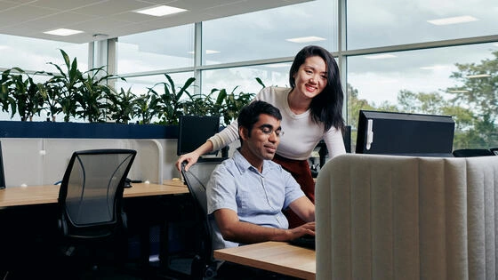 Two Deakin Graduate Certificate of Adult, Vocational Education and Training students look at a computer.