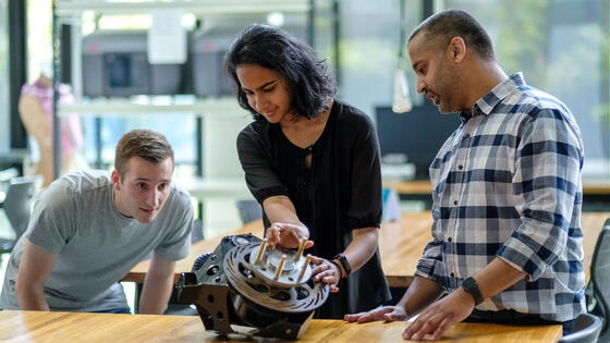Deakin postgraduate engineering students look at a mechanical device.