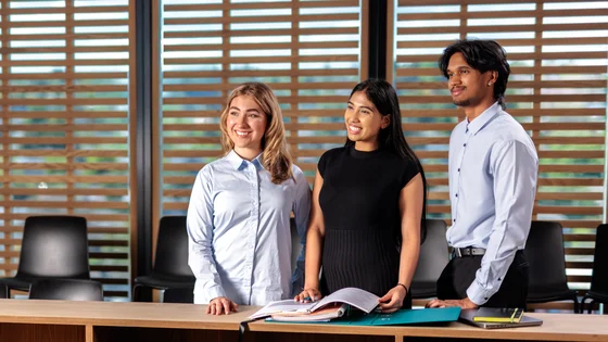 Three Law students standing in the Deakin Moot Court.