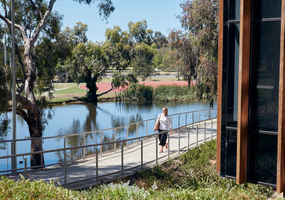 A student walks past a waterway at the Deakin Geelong Waurn Ponds Campus.