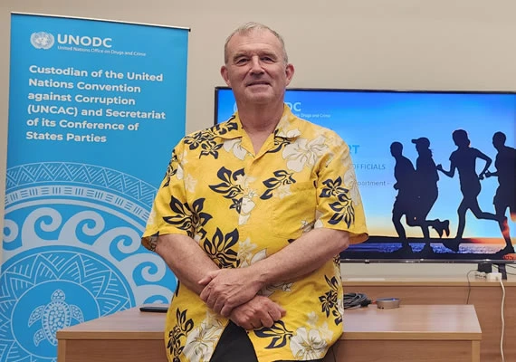 Deakin alumnus John Hyde with a UNODC banner in the background.