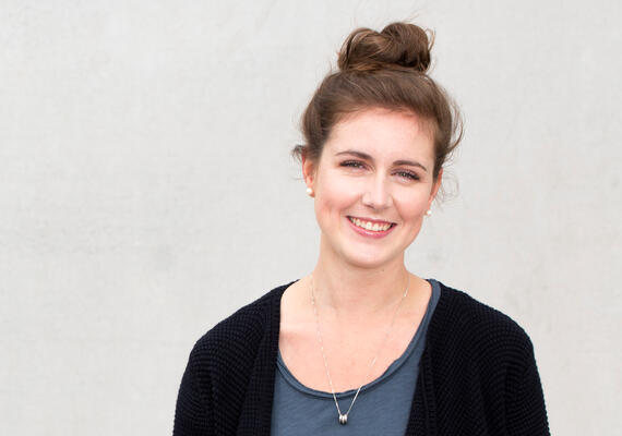 Sarah Whelan, a student in Deakin's Chinese language course, is standing in front of a grey wall..