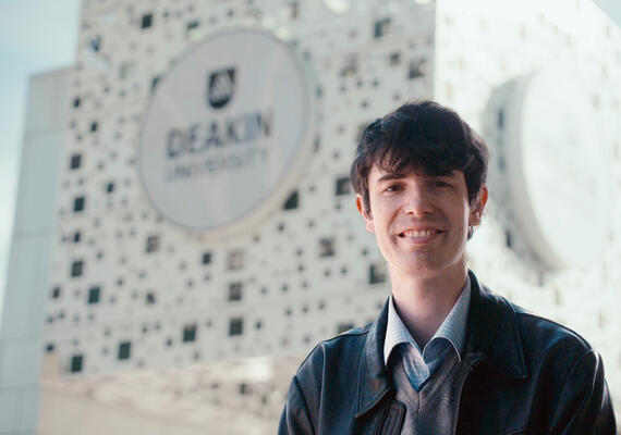 PhD candidate Alistair Macauley standing by the Deakin Cube. 