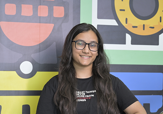 Deakin GIFT City student Kushi standing near a colourful wall