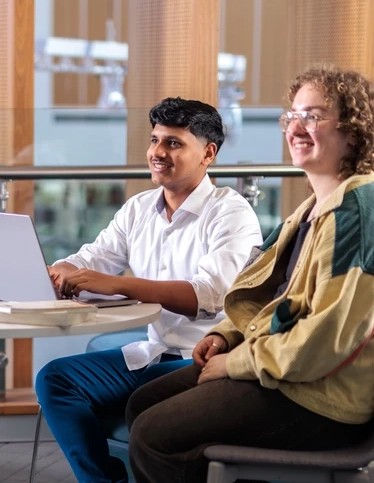 Two arts graduates sitting together at a laptop.