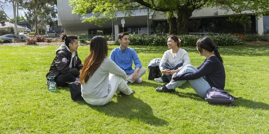 Students sitting on grass at the Melbourne Burwood Campus.
