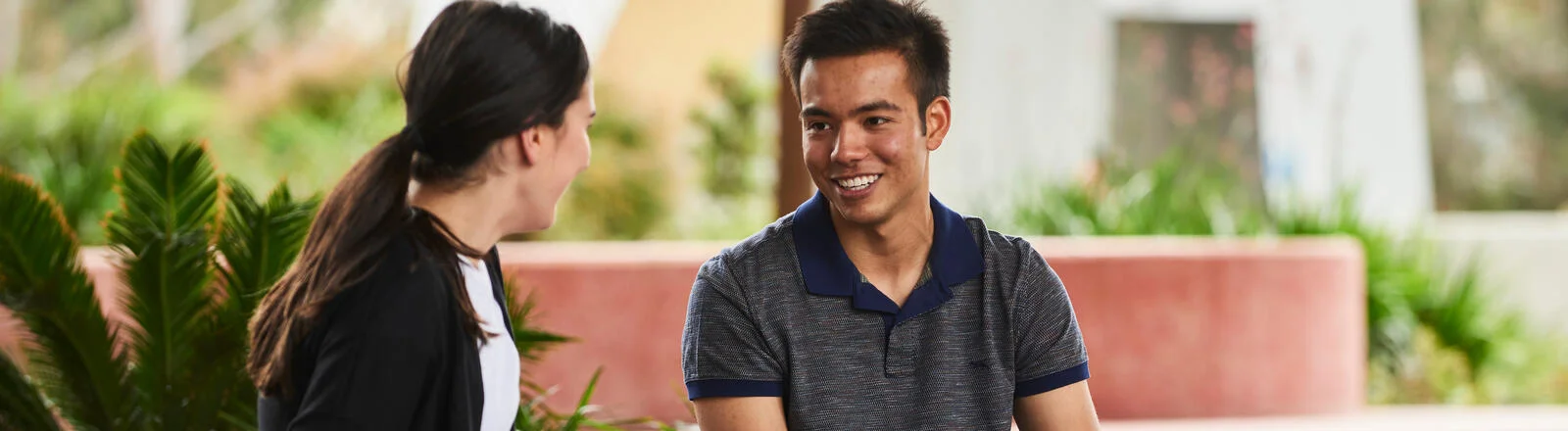 Two Deakin students chat on a bench. 