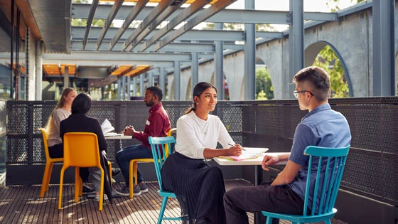 Two NSL students studying together, with one explaining their learnings to another student