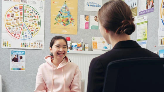 A Deakin postgraduate human nutrition students speaks to a young person in a clinic.