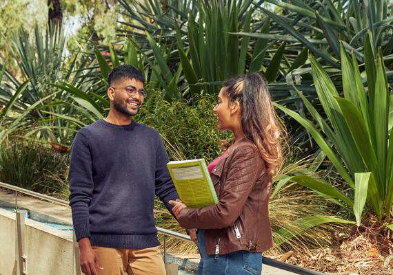 Two Deakin Waurn Ponds students lean against a railing talking and smiling