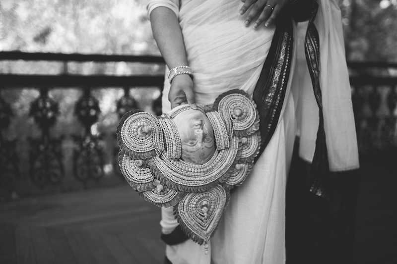 46463_800x533_glass_ochre_iron_mud_2025.jpg Black and white photograph of person wearing sari and holding a deity head