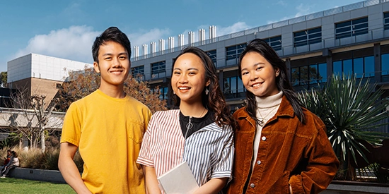 Three Deakin international students stand on a bridge 