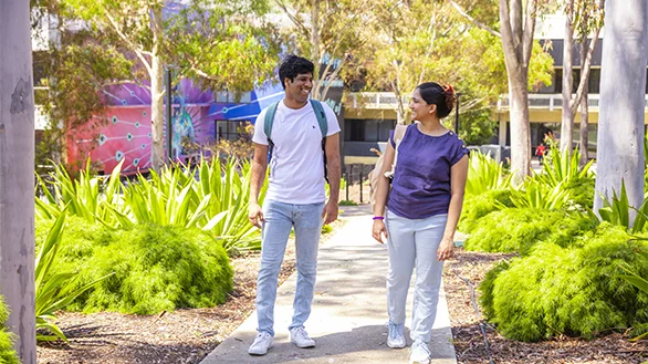 Two students walking among trees at Deakin Waurn Ponds campus