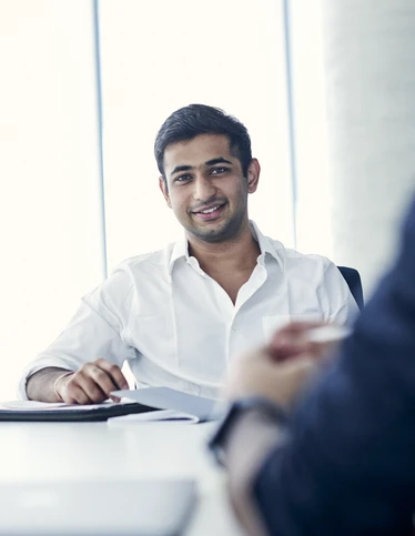 Commerce student sitting in a corporate meeting.