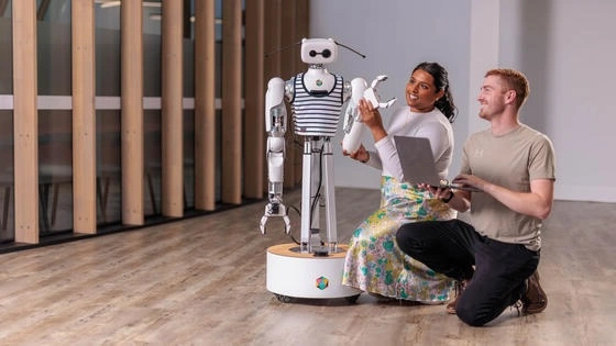 Humanoid AI Robot Reachy interacting with two students in the robotics lab.