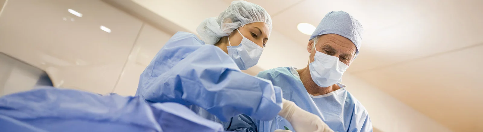 Two surgeons operating while wearing PPE.