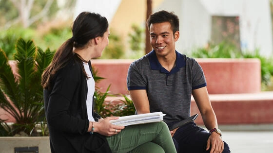 Two Deakin students chat on a bench. 
