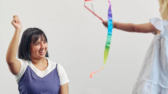Psychological science student engaging a child with toys and ribbon in a play-based learning setting.