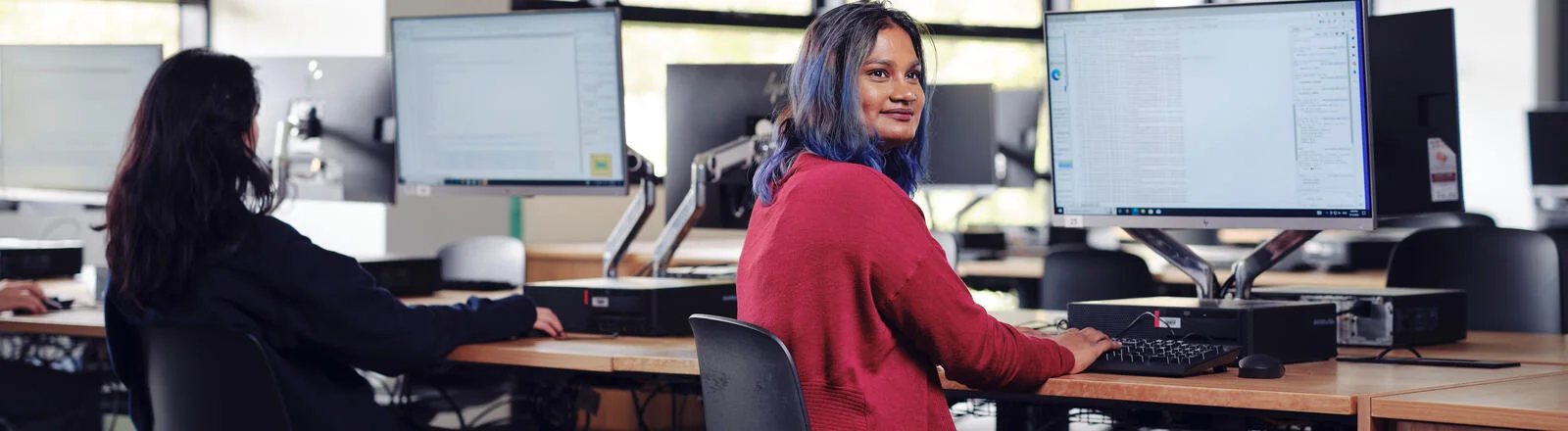 A Deakin postgraduate information technology student works at a desktop computer