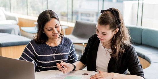 Two Deakin students study at a desk together on campus.