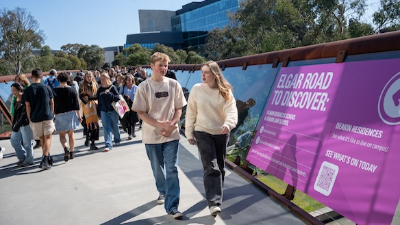 Two students walking on the bridge at Burwood on Open Day, surrounded by other students.
