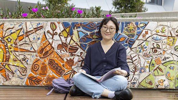 A student sitting in front of a brightly grafittied wall