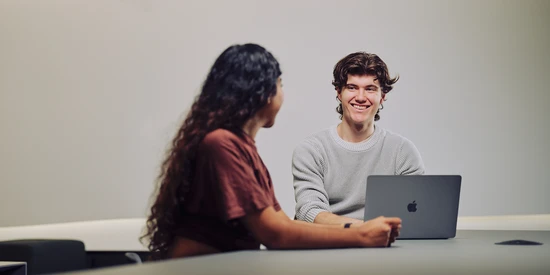 Two undergraduate students sit at an open laptop in the Law School Building on the Burwood campus.
