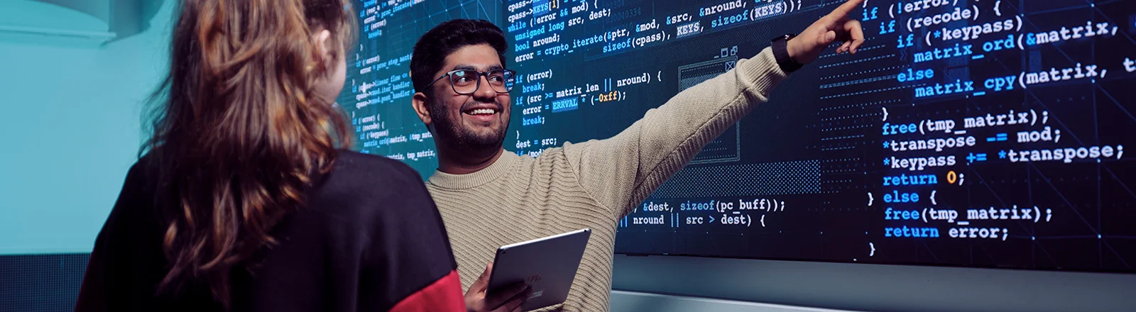 Two IT Deakin student talk in front of a screen of data.